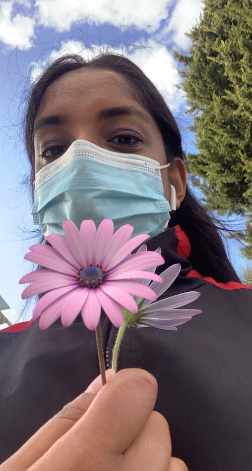 Young woman holds a flower to the camera on a walk
